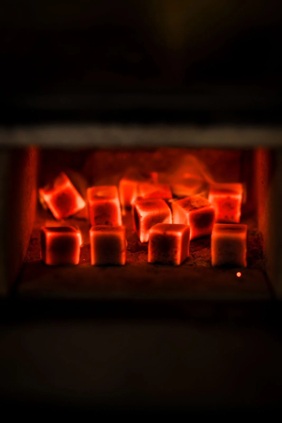Glowing hookah charcoal cubes in a coal heater, dark background